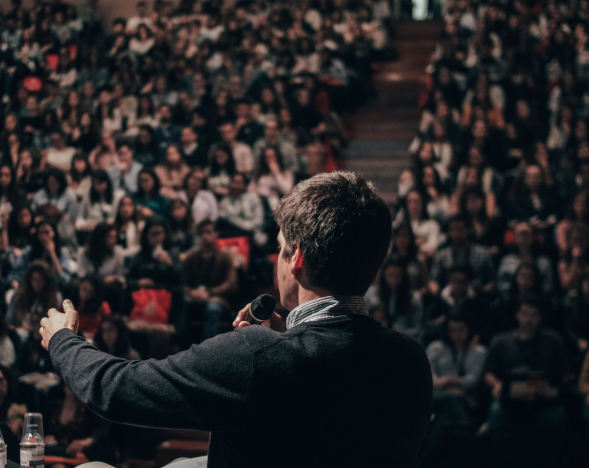 A man giving a speech to a crowded auditorium